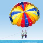 happy couple parasailing on tropical beach in summer