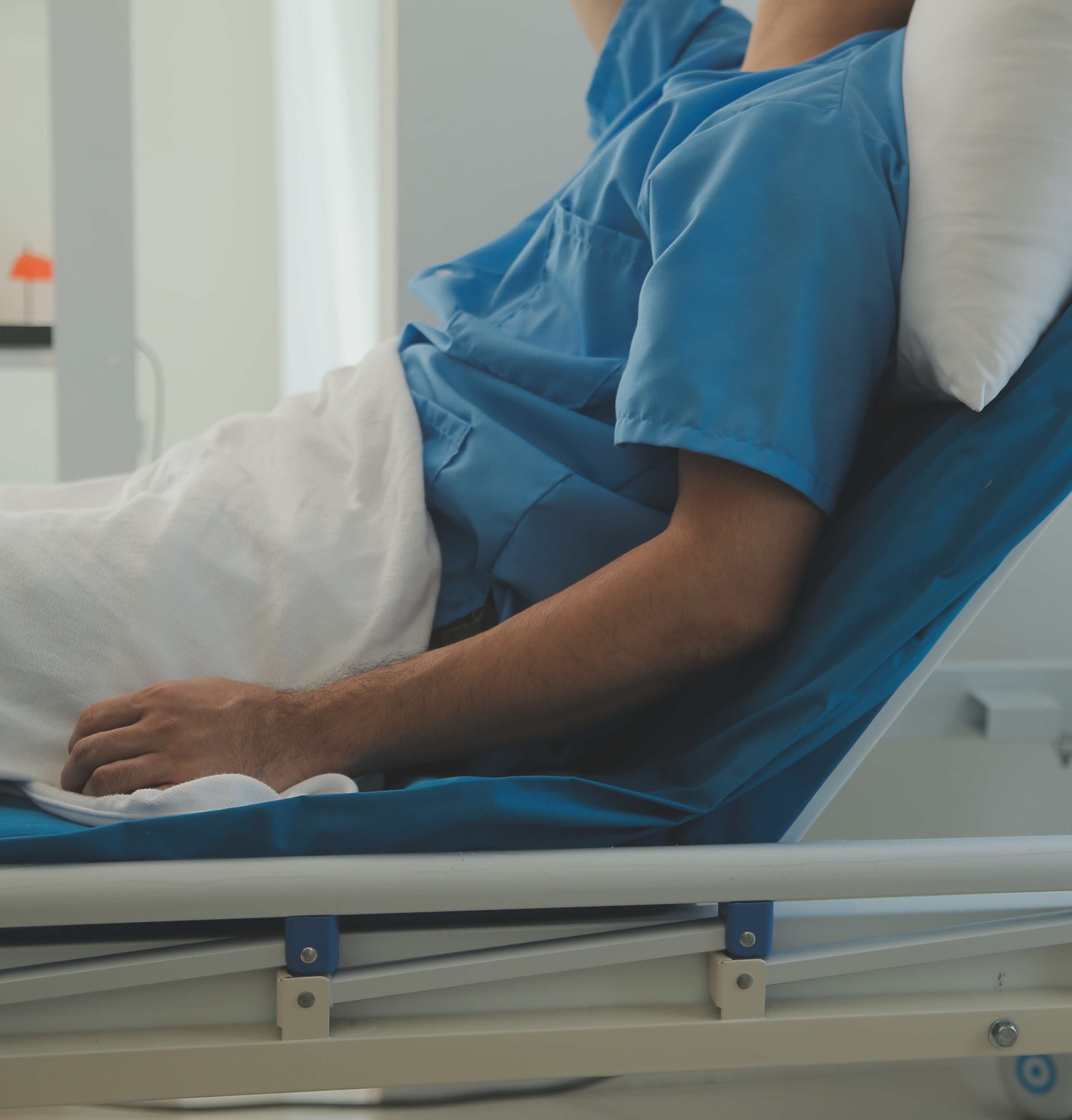 Seriously Ill Man Lying on a Bed in the Hospital after a Catastrophic Injury. Monitors Show His Vital Signs. Ward is Clean and New